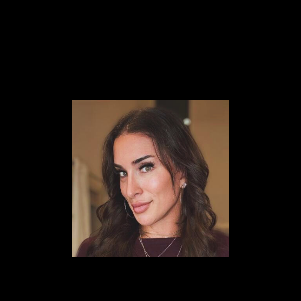 Gabbi with long dark hair and makeup, wearing a necklace, against a neutral background.